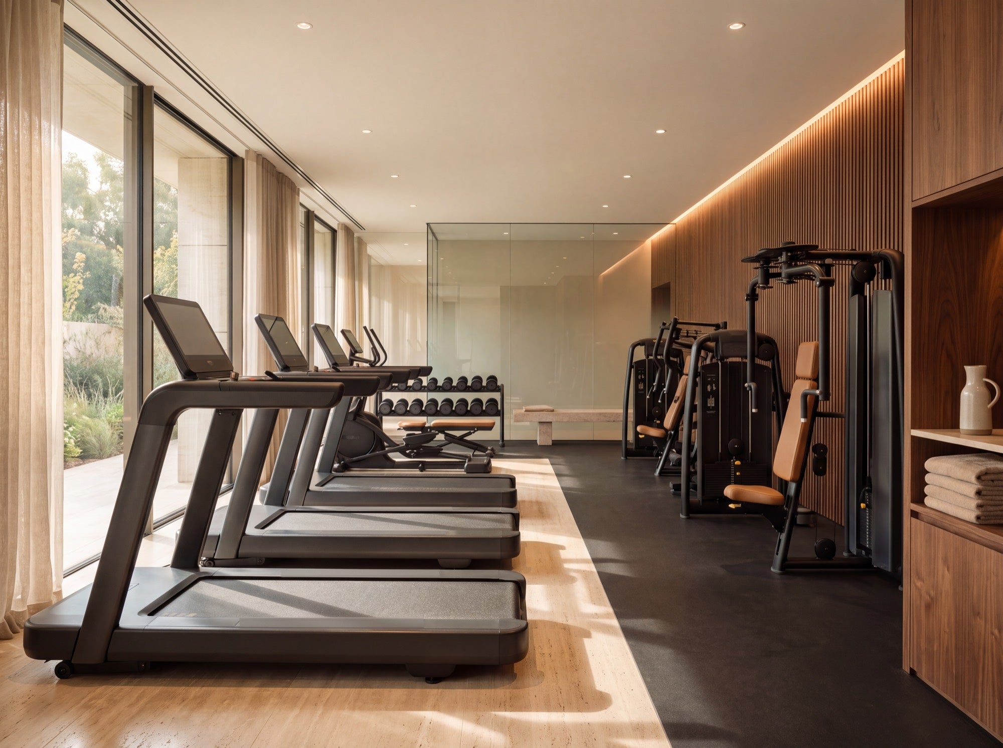 Gimnasio de hotel terminado con máquinas de cardio frente a un ventanal.