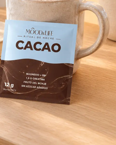 Un sobre de Cacao Ritual apoyado en una taza de cacao.
