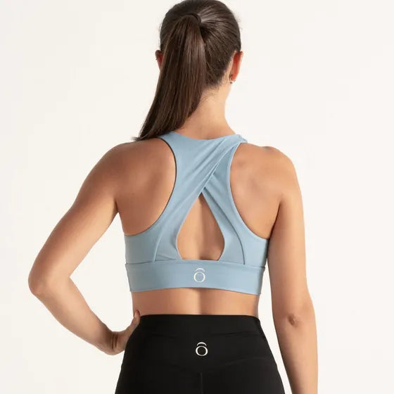Top azul claro con una abertura en la espalda, visto por detrás, con un legging negro.