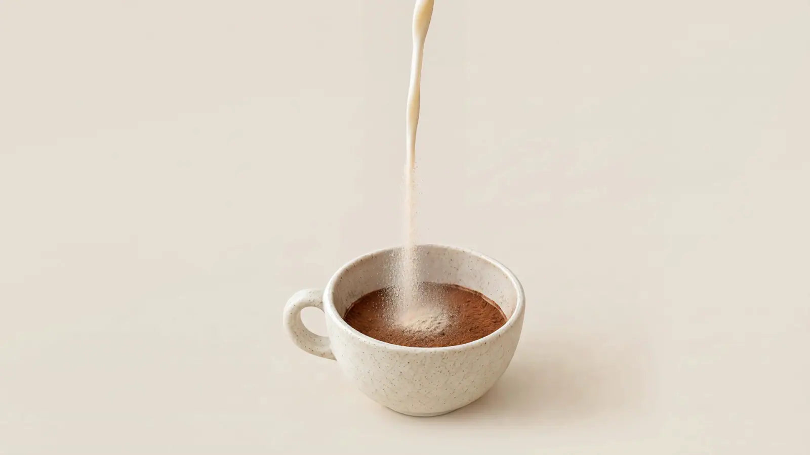 Un hilo de leche se convierte en polvo fino y cae en la taza, sobre el cacao.